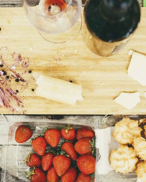 A table full of cheese, fruit and glasses of wine from above
